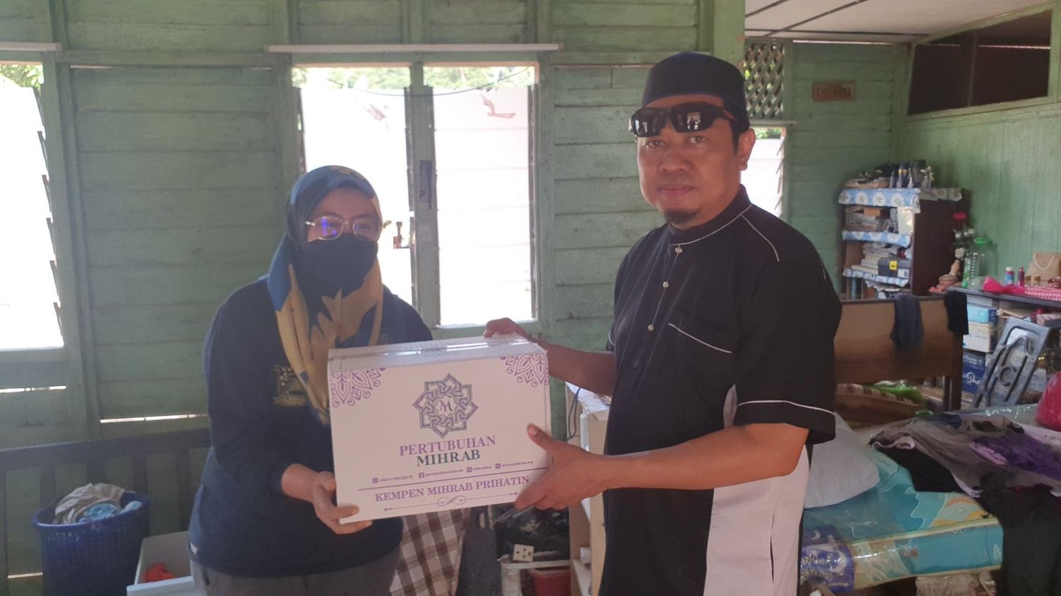 Penyerahan kotak bantuan kepada penerima di rumah