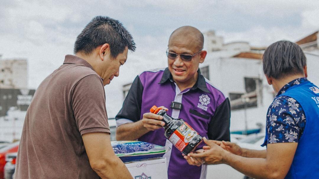 Wakil Yayasan Mihrab mengagihkan bantuan keperluan kepada penerima.